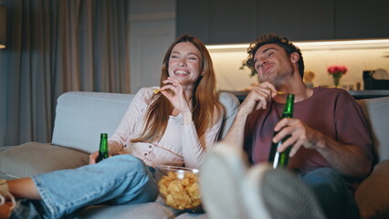 Loving couple watching movie sitting night closeup. Happy family clinking beer