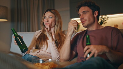 Two friends discussing movie at late apartments closeup. Lovers toasting beer