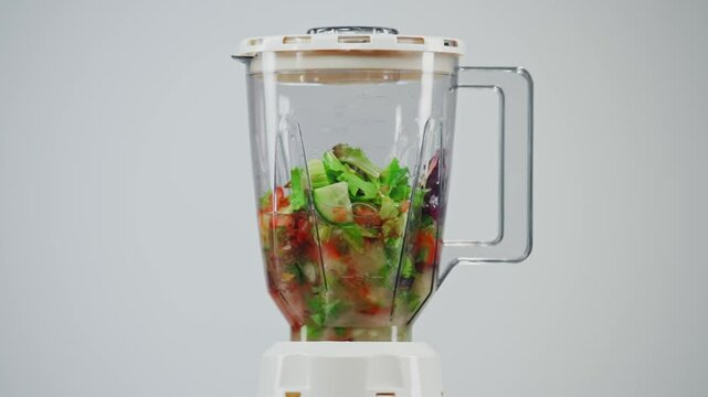Water and ingredients for vegetable smoothie are mixed in a blender
