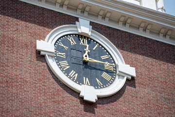 a clock on a bricks wall showing Boston time