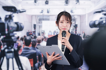 記者会見場からレポートをする女性記者