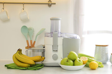 Modern juicer and fruits on white counter in kitchen