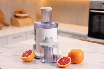 Modern juicer and fresh grapefruits on white marble table in kitchen