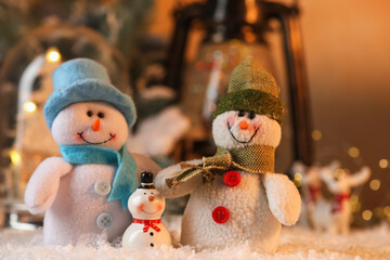 Funny snowman figures on artificial snow against blurred background