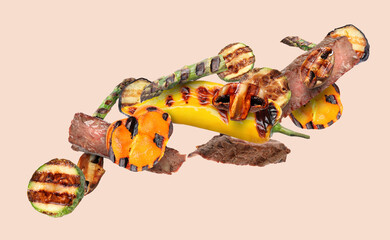 Grilled meat, vegetables and mushrooms in air on dark beige background