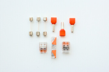 Electrical cable and wiring components, including accessories like fuses, terminals, wire splice connectors isolated on white background. Tidy electrician workshop table, parts for industrial work.