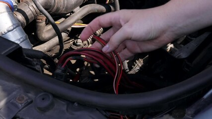 The mechanic holds wires in his hands, selecting the right ones, and organizing connectors for electrical equipment in a car. Transportation concept. 