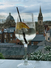 one cocktail sit on a table in Oxford, overlooking the historic city skyline with iconic buildings...