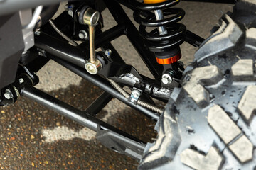 Close-up of an off-road vehicle's suspension system featuring a coil spring and tire. The setting...
