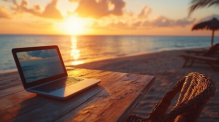 A laptop rests on a wooden table overlooking a breathtaking ocean sunset.