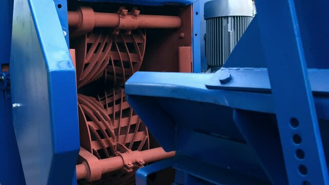 Industrial wood debarking machine with rotating components on woodworking plant. Woodworking industry, modern equipment on factory. Part of conveyor line. Engineering technology in production.