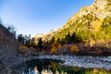 Autumn view of a lake in the mountains. Fallen leaves in the water