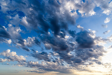 Beautiful white puffy clouds against blue sky during dramatic sunset