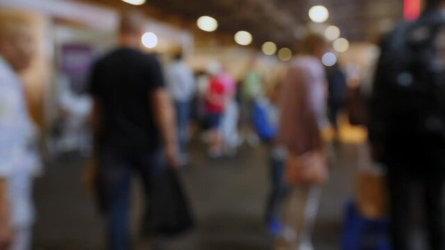 A large crowd forms a line in a bustling convention center during a lively event. Attendees are engaged and socializing while they wait.