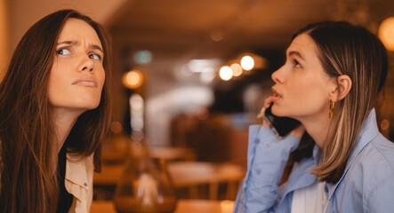 Curious woman secretly listening to friend sister talking on mobile phone with resting in cafe....