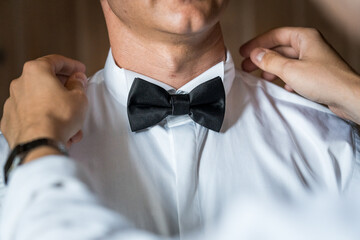 Elegant Preparation: Gentleman Adjusting Classic Black Bow Tie for a Formal Event