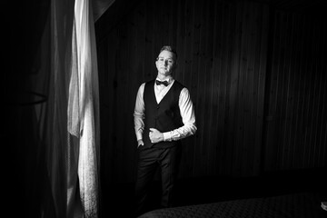 Elegant Portrait of a Man in Formal Attire with Dramatic Lighting in a Wooden Interior