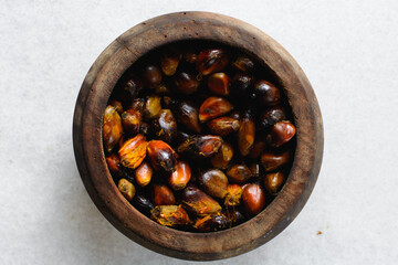 Overhead view of fresh palm nuts in a wood mortar, top view of palm nuts for making palm oil being pounded using a wooden mortar and pestle, process of making palm oil and nigerian banga soup