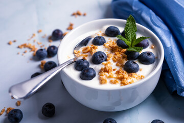 Healthy light diet breakfast of blueberries and yogurt and crunchy granola and mint leave