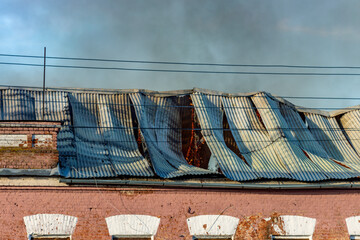A building with a roof that is torn off and has a lot of smoke coming out of it © Sergei