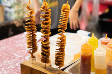 Crispy fry potato twister on a skewer from the stall with spicy sauces