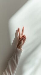 Hand showing peace sign against a white