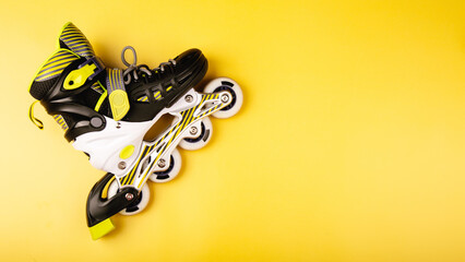 rollerblades laying down isolated on a yellow background