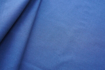 Navy blue cotton fabric background. Plain satin textile template with neat folds, copy space, perspective view, close-up, texture and details. Backdrop with new monochromatic material.