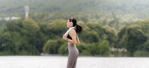 Lakeside Tranquility: A young woman pauses her workout, embracing the serene beauty of a misty...