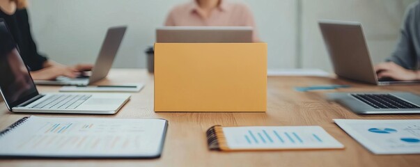 Team in a conference room with laptops, notebooks, and charts, collaborative multitasking, business strategy
