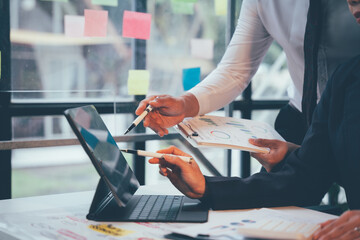 Business Strategy Collaboration:  A close-up shot of two professionals engaged in a collaborative discussion, using a tablet and charts to analyze data and strategize for success. Their focused expres