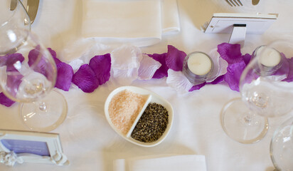 Section of a table at a wedding reception decorated with white and purple flower petals