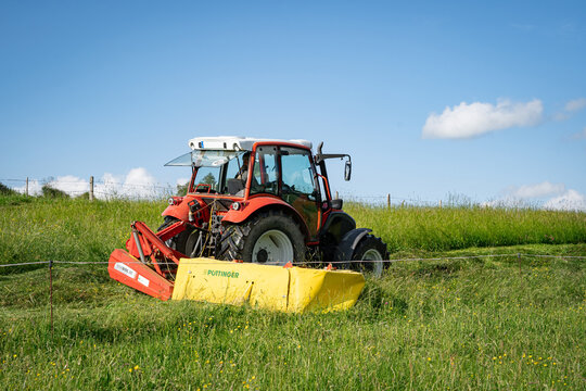 Kleiner  Lindner Traktor mit einem Pottinger Kreiselm&auml;her beim M&auml;hen von Gras f&uuml;r Heu oder Grassilage im Allg&auml;u.