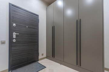 A fragment of an entrance hall with an elegant interior. Light floor, dark gray .entrance door and...