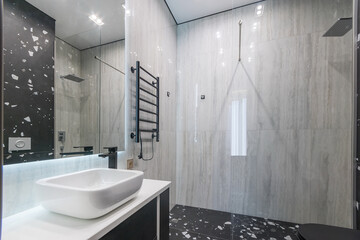 The bathroom is decorated in gray tones, with a stylish interior design. Shower with a .tropical watering can.