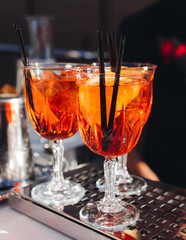 Bartender working, beautiful row line of different coloured liquor alcohol cocktails on a open air party in a bar, and others on catering banquet on event, barman mixing drinks and beverages in club