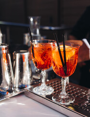 Bartender working, beautiful row line of different coloured liquor alcohol cocktails on a open air party in a bar, and others on catering banquet on event, barman mixing drinks and beverages in club
