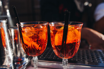 Bartender working, beautiful row line of different coloured liquor alcohol cocktails on a open air party in a bar, and others on catering banquet on event, barman mixing drinks and beverages in club