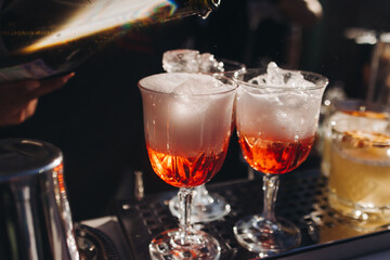 Bartender working, beautiful row line of different coloured liquor alcohol cocktails on a open air party in a bar, and others on catering banquet on event, barman mixing drinks and beverages in club