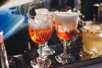 Bartender working, beautiful row line of different coloured liquor alcohol cocktails on a open air party in a bar, and others on catering banquet on event, barman mixing drinks and beverages in club