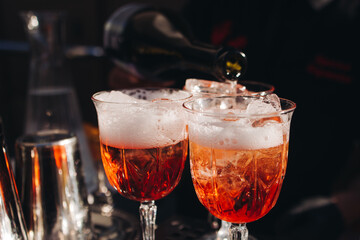 Bartender working, beautiful row line of different coloured liquor alcohol cocktails on a open air party in a bar, and others on catering banquet on event, barman mixing drinks and beverages in club