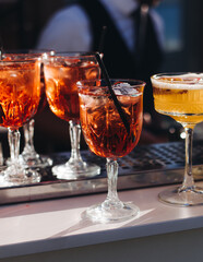 Bartender working, beautiful row line of different coloured liquor alcohol cocktails on a open air party in a bar, and others on catering banquet on event, barman mixing drinks and beverages in club