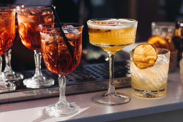 Bartender working, beautiful row line of different coloured liquor alcohol cocktails on a open air...