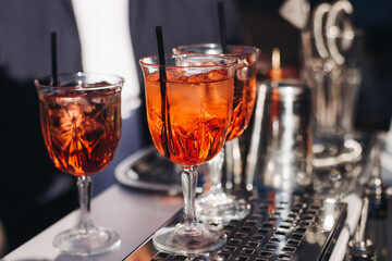 Bartender working, beautiful row line of different coloured liquor alcohol cocktails on a open air party in a bar, and others on catering banquet on event, barman mixing drinks and beverages in club
