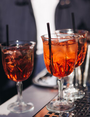 Bartender working, beautiful row line of different coloured liquor alcohol cocktails on a open air party in a bar, and others on catering banquet on event, barman mixing drinks and beverages in club