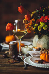 Cozy festive holiday table decor for home family Thanksgiving dinner. Traditional event, elegant natural decoration. Wooden rustic table, countryside style. Burning candles, floral centrepiece pumpkin
