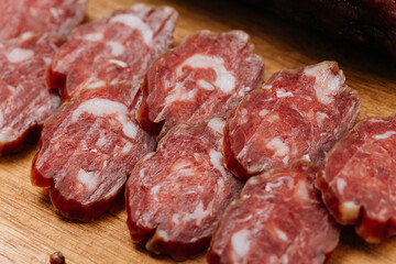 Close-up of thinly sliced salami on a wooden board, showcasing rich marbling and gourmet quality