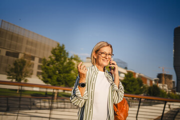 Fototapeta premium mature woman have phone call on mobile phone and stand on the bridge