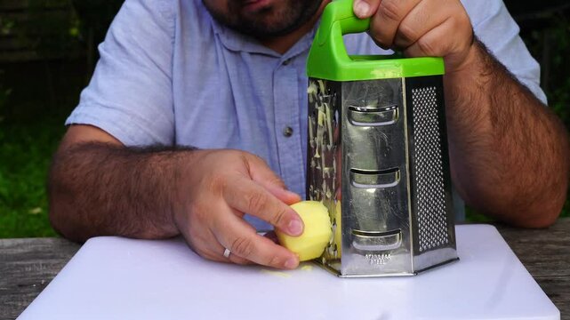Man rubs potatoes on a grater