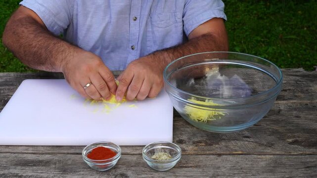 Man rubs potatoes on a grater